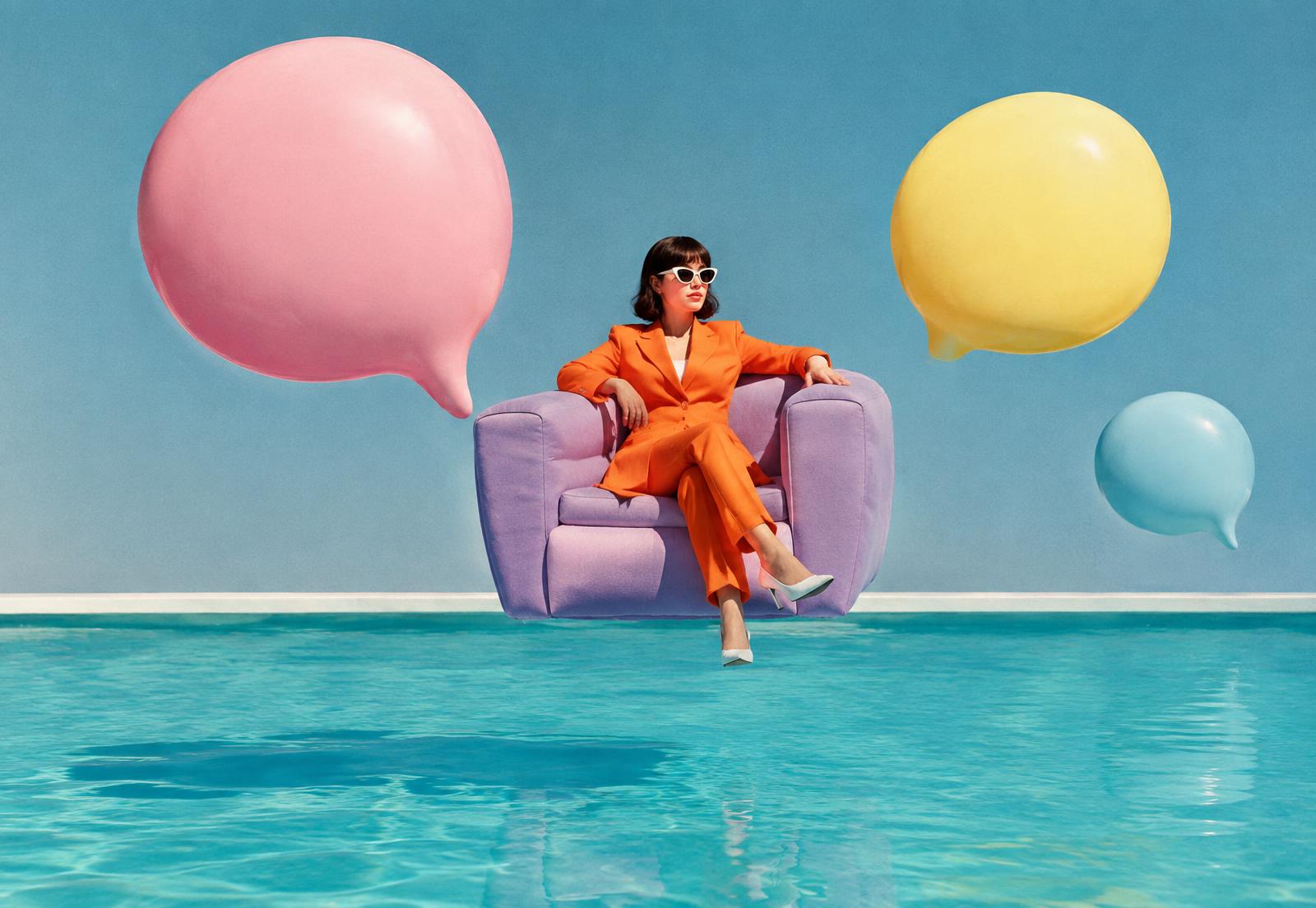 A woman in an orange suit sitting on a floating lilac armchair above a pool, surrounded by speech-bubble balloons