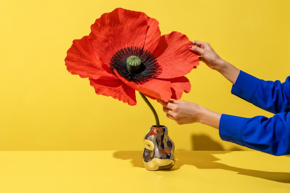 Hands carefully shaping an oversized red paper flower